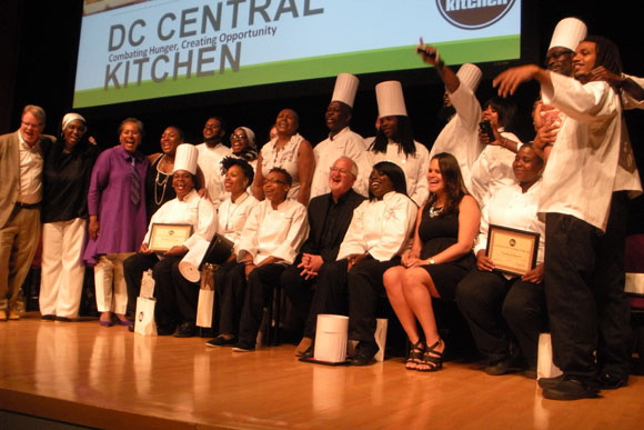Class 100  of the DC Central Kitchen's culinary job training program pose for a group photo with founder Robert Egger (center)